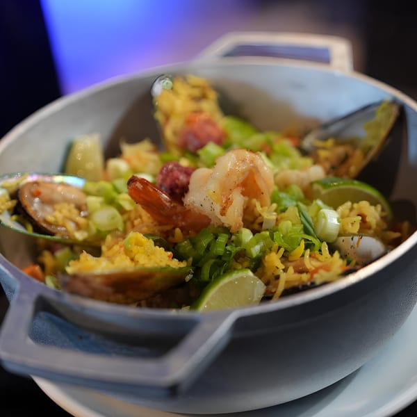 Blue Salt Restaurant's paella with shrimp, mussels, chorizo, and lime in a metal pot.